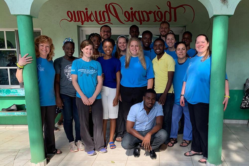 Group of physical therapy students and professors pose for group photo outside Haitian medical clinic