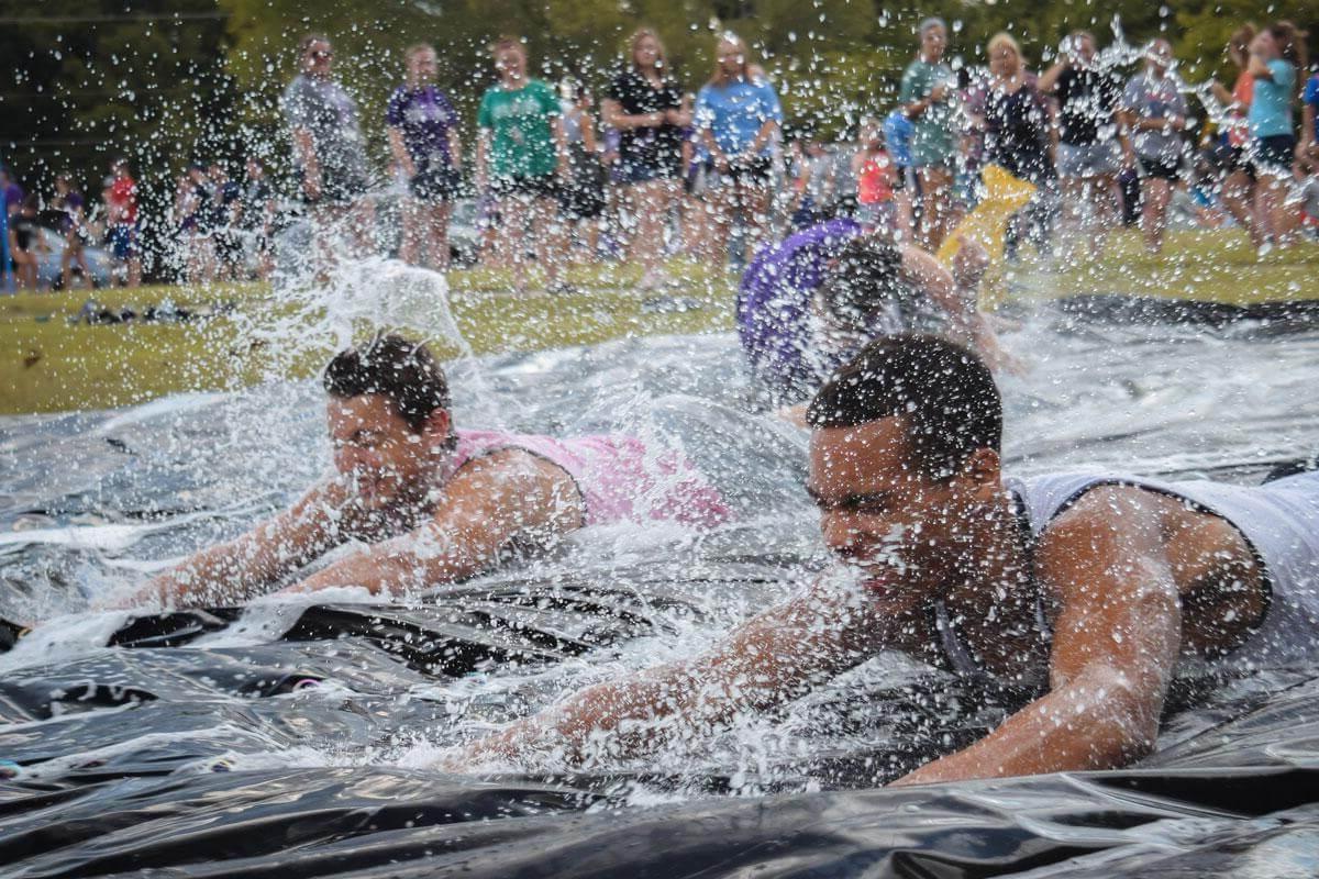 Two male students in action shot going down slip and slide
