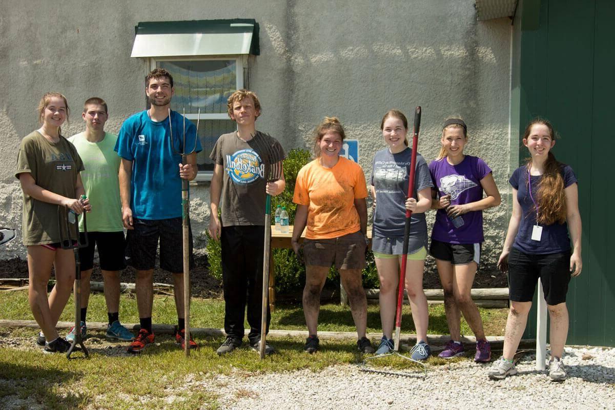 group of eight students pose for picture while doing yard work for service project