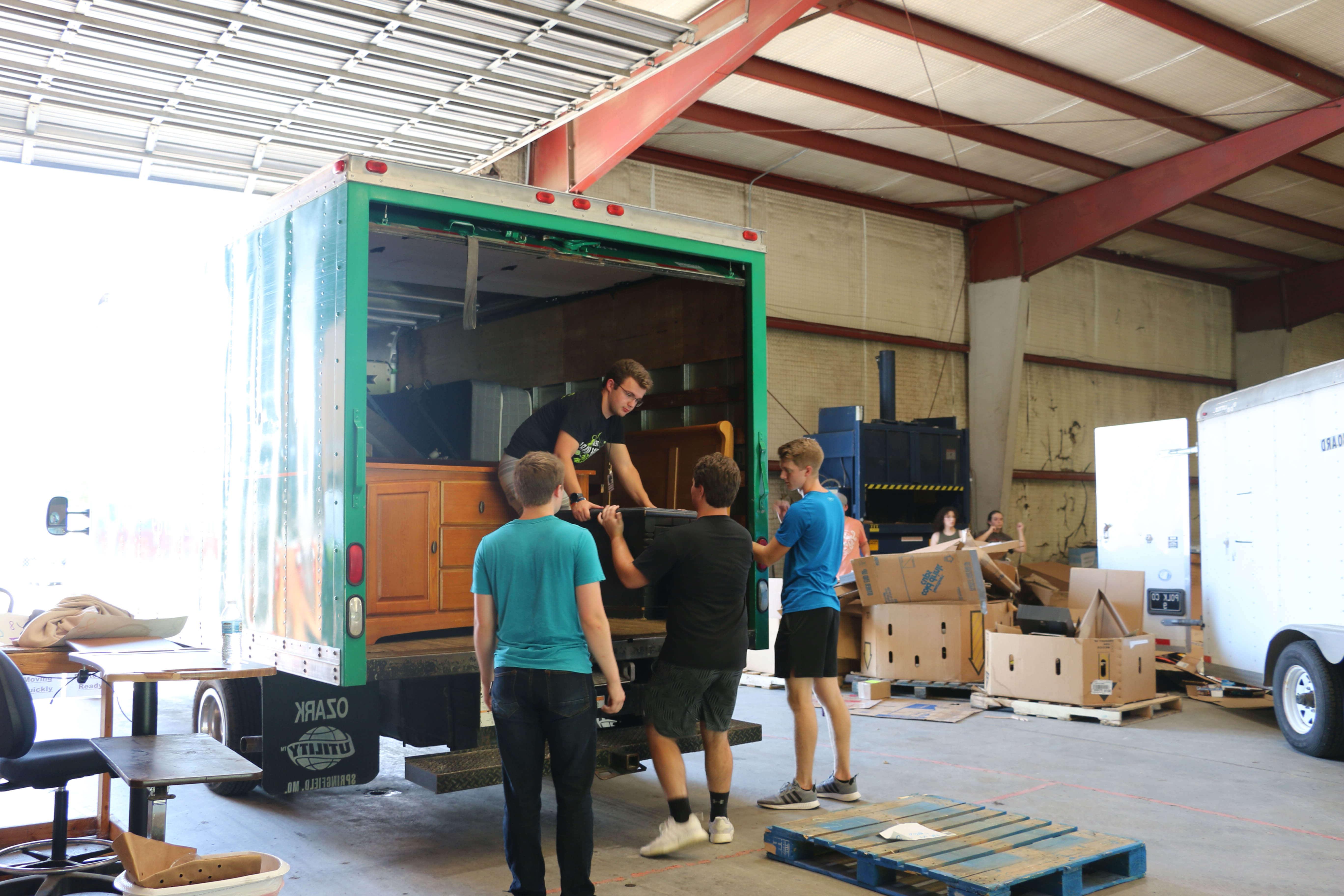 students serve by unloading trailer of donated furniture in warehouse